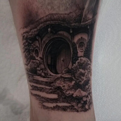 A black and grey tattoo by Brad Wallis showing the open front door of Bilbo's Hobbit House in the Shire