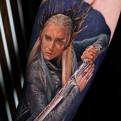 A colour realism tattoo by Nastasya Naboka showing Lee Pace as Thranduil holding his sword.