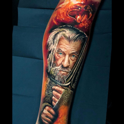 A colour realism tattoo by David Barrera showing Gandalf the Grey holding Glamdring with the Balrog in the distance behind him.