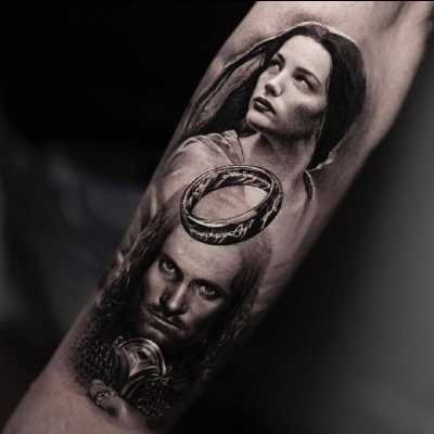 A black and grey realism tattoo by Inal Bersekov showing Aragorn and Arwen from the film adaptations of Lord of the Rings. There is a large One Ring at the centre of the portrait. Arwen looks away while Aragon stares straight out, holding his sword Andúril.