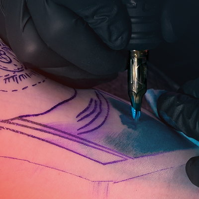 A close-up of someone getting blue shading in their tattoo.