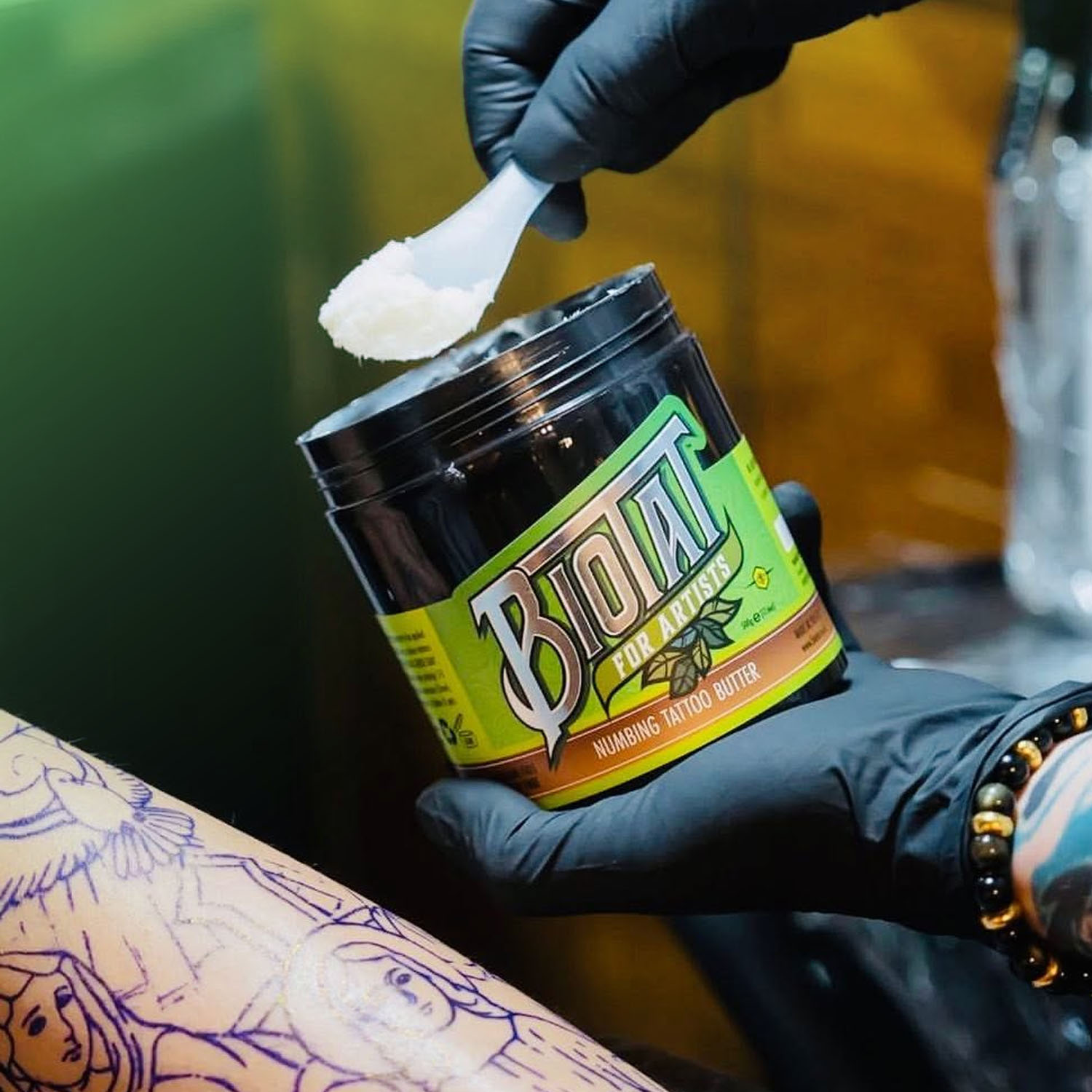 En skopa Biotat Numbing Tattoo Butter appliceras av en tatuerare