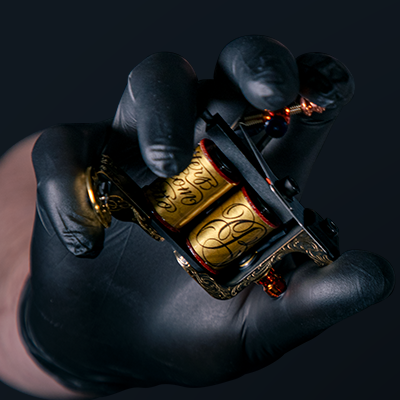 A coil tattoo machine in an artist's hands